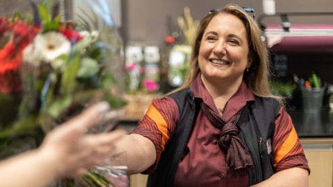 Floristikabsolventin Silvana Malito übergibt einen Blumenstrauss Floristikabsolventin Silvana Malito übergibt einen Blumenstrauss